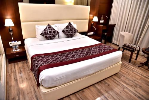 a hotel room with a large bed with pillows at Clarks Inn Suites Gwalior in Gwalior