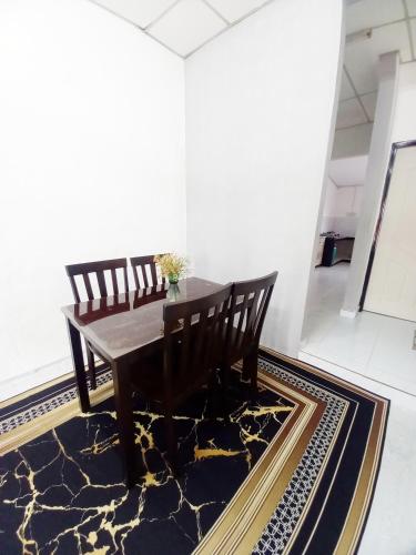 a dining room with a table and chairs on a rug at Perhentian Besut Homestay in Kuala Besut