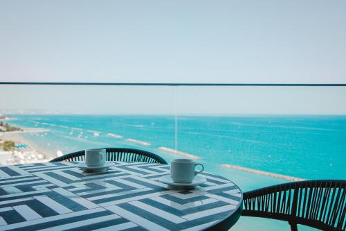a table with two coffee cups sitting on top of it at Stunning 1 Bed in Trilogy, Limassol Seafront in Limassol