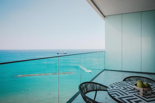 a balcony with a table and chairs and the ocean at Stunning 1 Bed in Trilogy, Limassol Seafront in Limassol