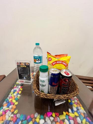 a basket of food and drinks on a table with candy at Hotel Woodlark Zirakpur II A Peaceful Stay I Travelers Choice I Best for Family and Group in Chandīgarh