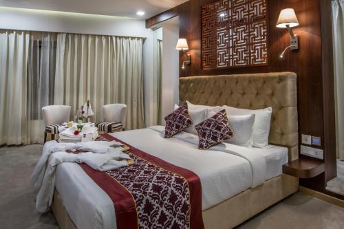 a hotel room with a large bed with white sheets at Clarks Inn Suites Gwalior in Gwalior