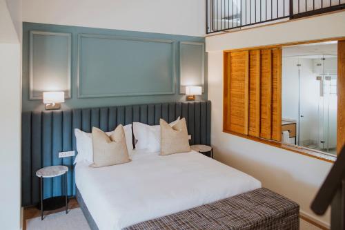 a bedroom with a large white bed and a mirror at Laborie Estate in Paarl