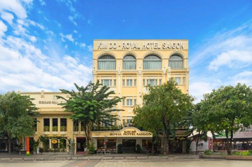 Ein hohes gelbes Gebäude mit einem Schild drauf. in der Unterkunft Royal Hotel Saigon in Ho-Chi-Minh-Stadt