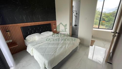 a bedroom with a bed with a black headboard at Green Guest House Malang in Kasri