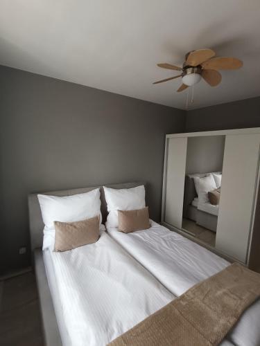 a bedroom with a white bed with a ceiling fan at Apartament Maria in Oświęcim