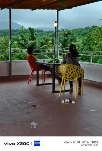 two people sitting at a table on a balcony at AM2PM Private Pool Villa in Badlapur