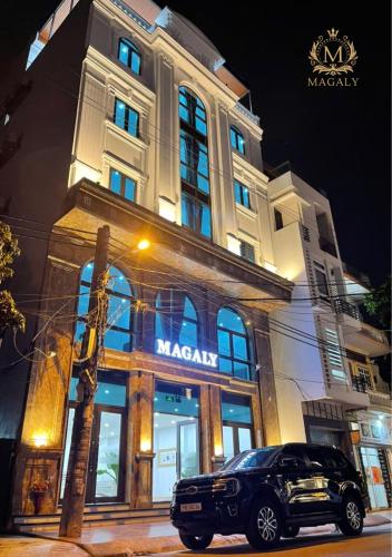 a car parked in front of a large building at Magaly Apartment & Hotel in Hai Phong