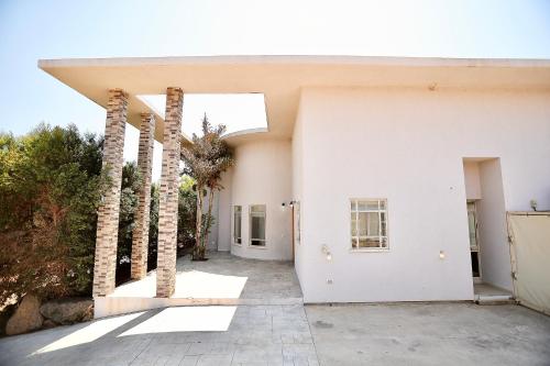 a white building with palm trees in a courtyard at פרדייז ריזורט in Had Nes