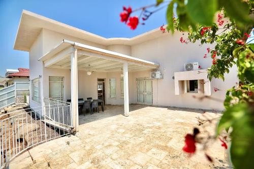 a white house with a patio and a dining area at פרדייז ריזורט in Had Nes