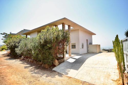 a white house with bushes in front of it at פרדייז ריזורט in Had Nes