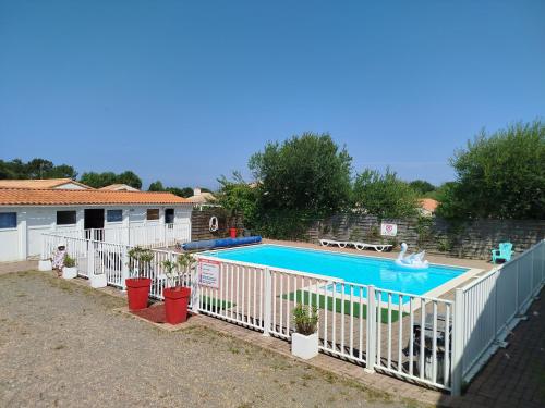 une piscine avec des plantes en pot et une clôture blanche dans l'établissement L'Océane ( Résidence La Joséphine ), à Les Sables-dʼOlonne
