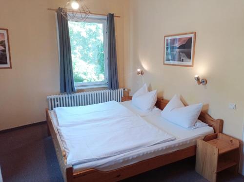 a bedroom with a bed with white sheets and a window at Pension Sonnenhof in Braunlage
