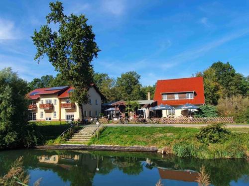 a house with a red roof next to a river at Gasthaus Bukoitza in Radensdorf