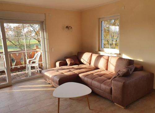 a living room with a brown couch and a balcony at Gasthaus Bukoitza in Radensdorf
