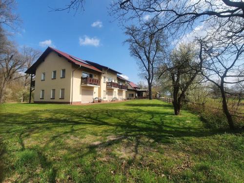 a large house on a grassy field with trees at Gasthaus Bukoitza in Radensdorf