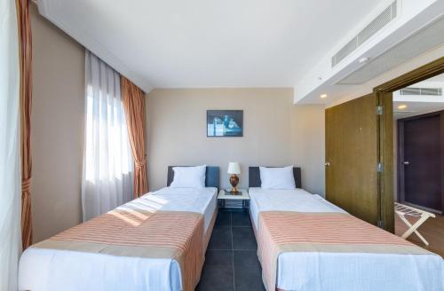two beds in a hotel room next to a window at Senza Sunset Beach Hotel in Alanya