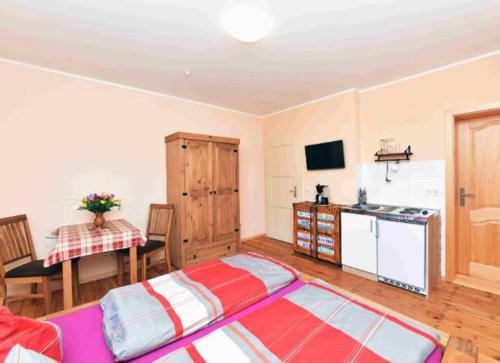 a living room with a table and a kitchen with a bed at Gasthaus Bukoitza in Radensdorf