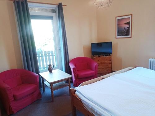 a bedroom with two chairs and a bed and a television at Pension Sonnenhof in Braunlage