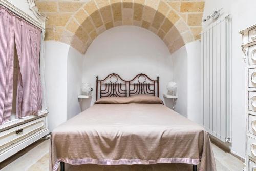 a bedroom with a bed with an arch above it at Il Gelsomino Bianco by BarbarHouse in Mottola