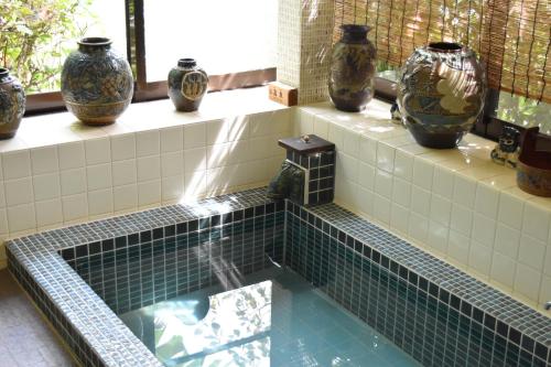 a hot tub with vases sitting on the ledge at Atami Southern Wind　 熱海 南風楼(温泉付) in Atami