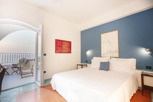 a bedroom with a white bed and a chair at Hotel Punta Scario in Malfa