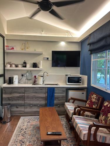 a living room with a kitchen with a ceiling fan at Sinurambi Cottage Rental in Penampang