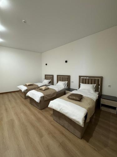 three beds in a room with white walls and wooden floors at MARCO Hotel in Goris