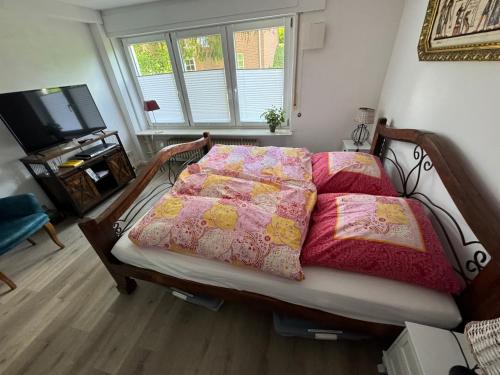a bedroom with a bed with pink and yellow quilts at Hummelglück - Ferienwohnung mit Terrasse in 30 Min in HH City in Bendestorf