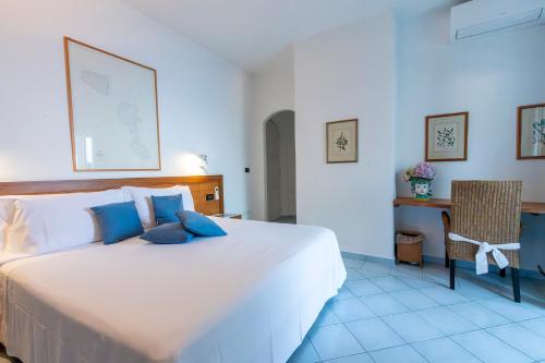 a bedroom with a large white bed with blue pillows at Hotel Punta Scario in Malfa