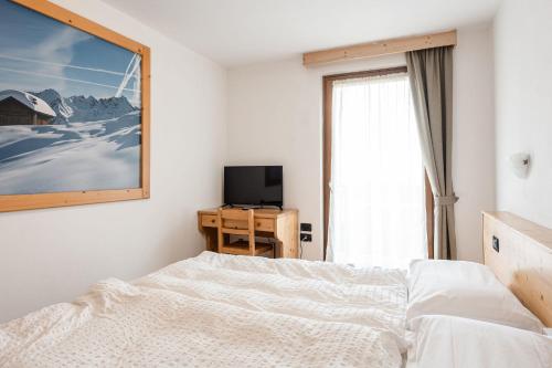 a bedroom with a bed and a tv and a window at Gaia Residence Hotel in Mezzana