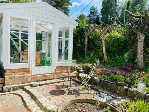 a greenhouse in a garden with a table and chairs at Charming Cottage near Beach & Nature in Sarpsborg