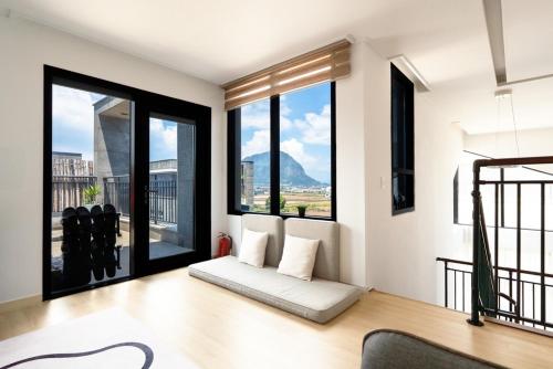 - un salon avec de grandes fenêtres et un canapé dans l'établissement Jeju Jebistay, à Sagye-ri