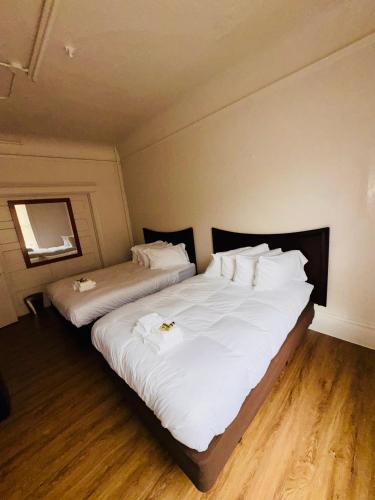 two beds in a room with white sheets and pillows at Riviera Hotel in San Francisco