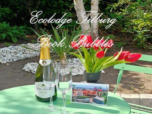 a bottle of wine and two glasses on a table at Ecolodge Tilburg met zwembad in groene oase bij centrum in Tilburg