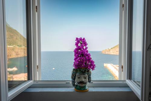 a vase with a mask with purple flowers on a window at Hotel Punta Scario in Malfa
