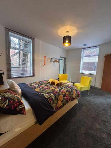 a bedroom with a bed and two yellow chairs at 2 Newcastle Street in Crewe