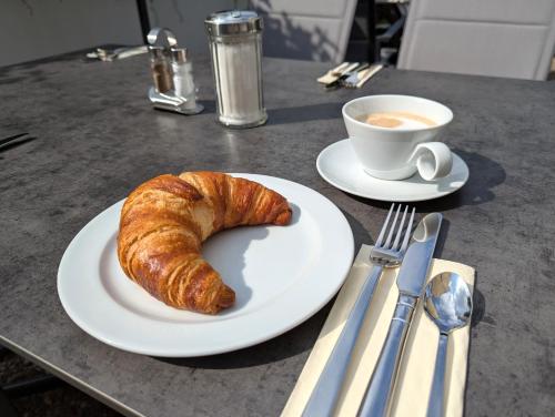 a plate with a croissant and a cup of coffee at City Hotel Stuttgart in Stuttgart