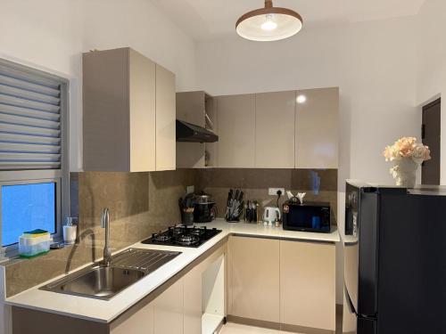 a kitchen with a sink and a black refrigerator at Zeleny Santorini in Negombo