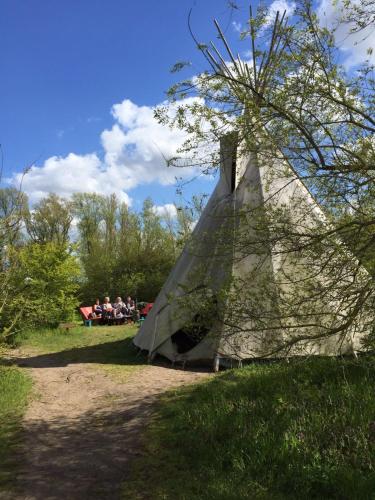 a group of people sitting around a teepee in a field at CampSpirit in Biddinghuizen