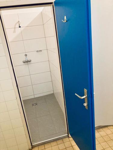a shower with a blue door in a bathroom at NUMBR25 - self service & low budget Hotel in Graz