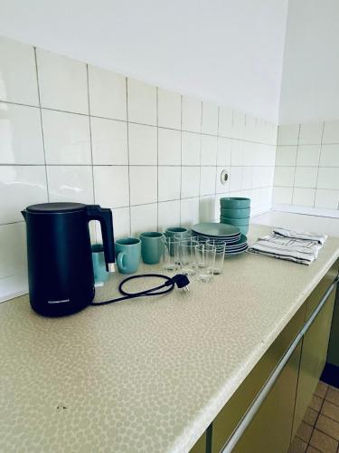 a kitchen counter with glasses and plates and a coffee maker at NUMBR25 - self service & low budget Hotel in Graz
