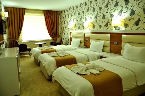 a hotel room with three beds with towels on them at The Ancient Mesopotamia Hotel in Batman