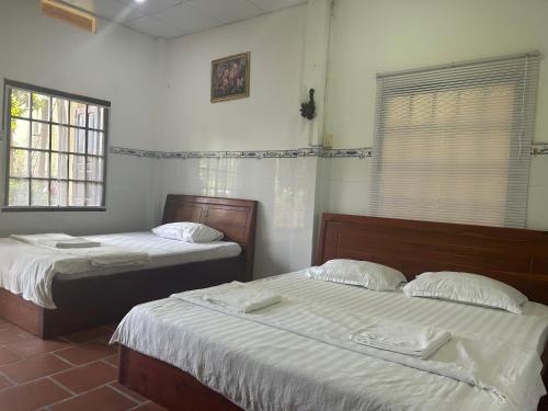Dos camas en una habitación con dos ventanas. en Bungalow COCO CHILL PQ, en Phu Quoc