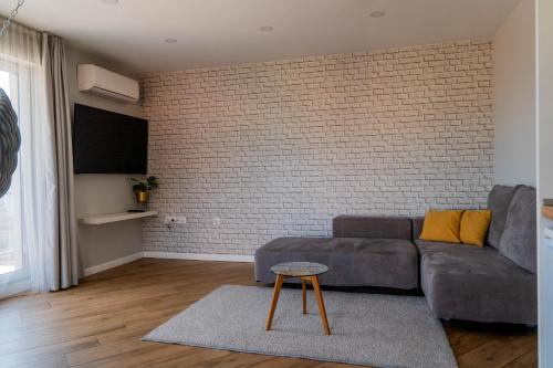 a living room with a couch and a brick wall at "The House" Апартаменти и Термална зона in Velingrad