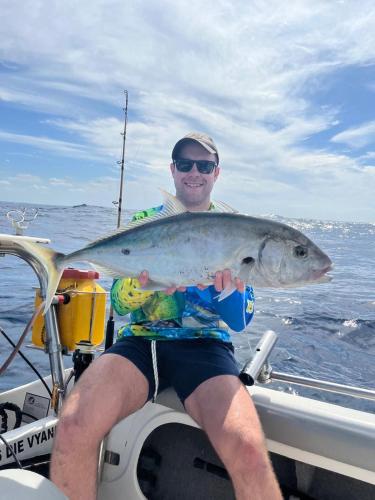 a man sitting on a boat holding a fish at Linga Bay Retreat in Morrumbene