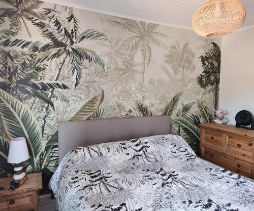 Un dormitorio con una cama con papel pintado tropical. en LA VILLA MONTA, en Vendays-Montalivet