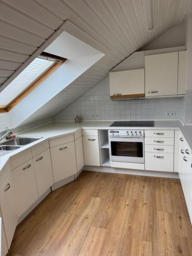 an attic kitchen with white cabinets and a skylight at Haus Mechthild Sindelfingen-Maichingen Self Check-In in Sindelfingen