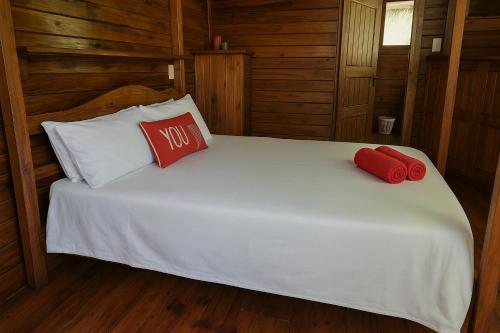 a white bed with two red pillows on it at Linga Bay Retreat in Morrumbene