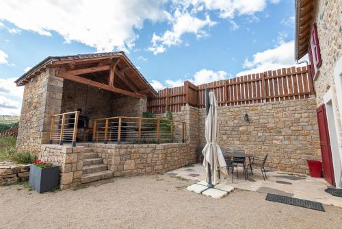 a stone building with a table and a umbrella at Gite le crespin in Antrenas